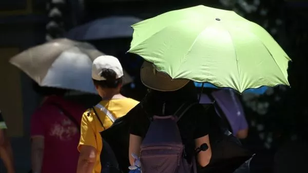 Personas con sombrilla en el calor. Foto referencial del tiempo en Santiago en elecciones