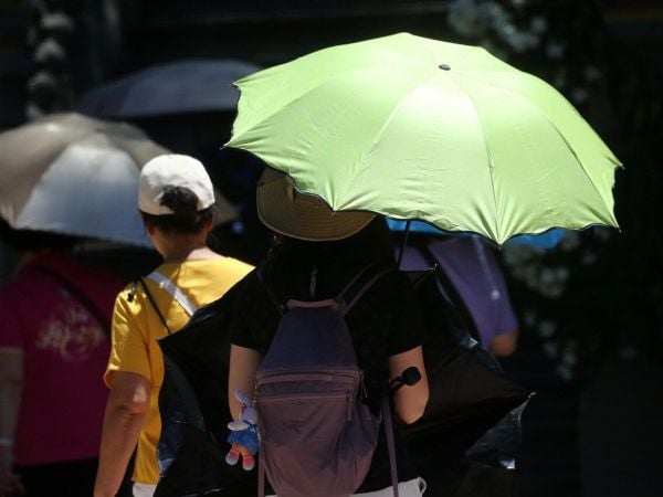 Personas con sombrilla en el calor. Foto referencial del tiempo en Santiago en elecciones
