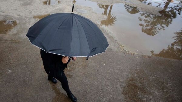 Persona bajo la lluvia con paraguas.