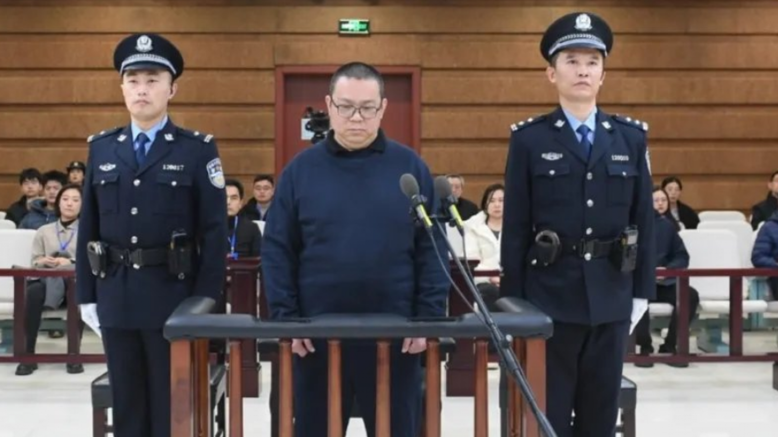 Bai Tianhui junto a dos policías al costado.
