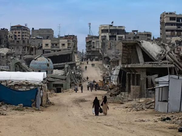 Mujeres caminando en Gaza mientras a su alrededor está todo destruido por la guerra.