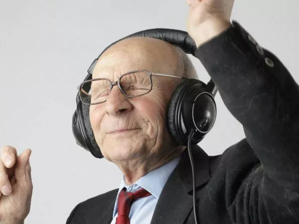 Persona adulta mayor escuchando música con audífonos como estimulación cognitiva.