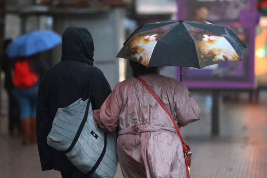 Personas caminando con paraguas bajo la lluvia. Lluvia en Santiago