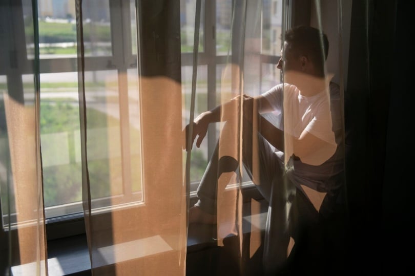 Hombre mirando por una ventana. Luz natural