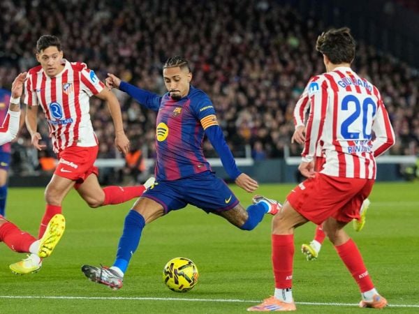 Raphinha lanzando un tiro frente a jugadores del Atlético de Madrid