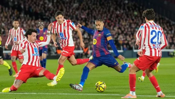 Raphinha lanzando un tiro frente a jugadores del Atlético de Madrid