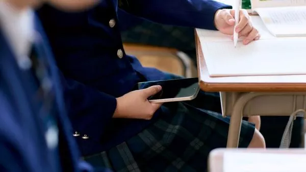 Niña con celular en la sala de clases