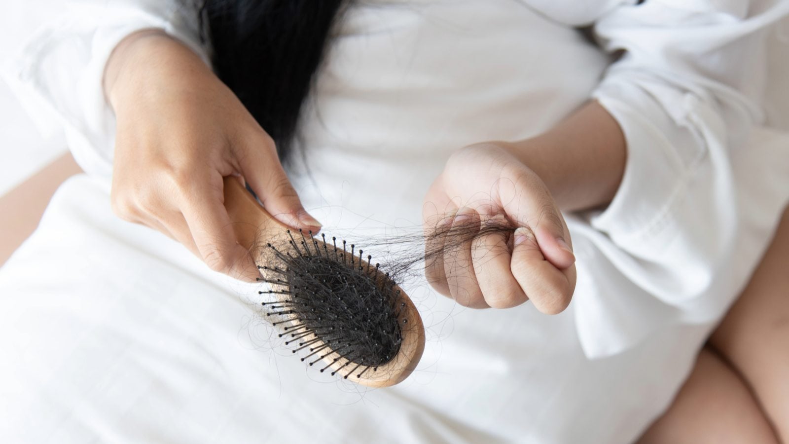 Una mujer sostiene un cepillo quitándole el pelo que se quedó enredado