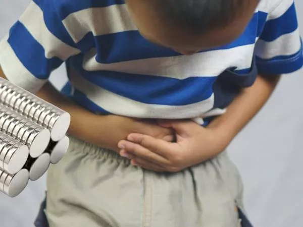 NIño tomándose el abdomen junto a unos imanes