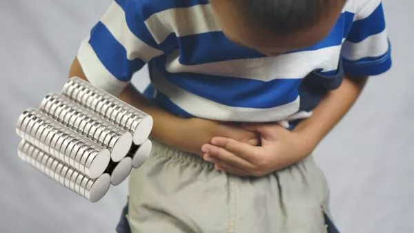 NIño tomándose el abdomen junto a unos imanes