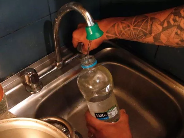 Persona llenando una botella con agua en una cocina