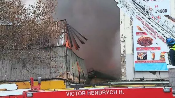 Incendio afecta a locales comerciales en Santiago: hay cortes de tránsito en Alameda Equipos de Bomberos trabajan en el lugar para controlar las llamas y evitar la propagación del fuego a edificios colindantes.