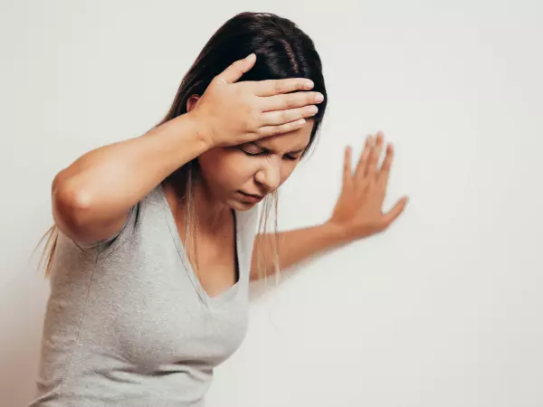 Mujer se toma la cabeza por dolor