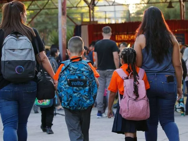 Estudiantes con mochilas entrando a clases
