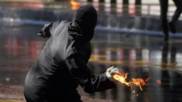 Encapuchado lanzando una bomba molotov