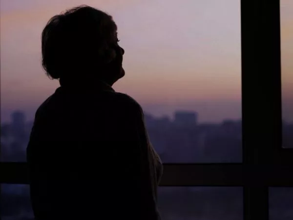 Mujer mira por la ventana al horizonte.