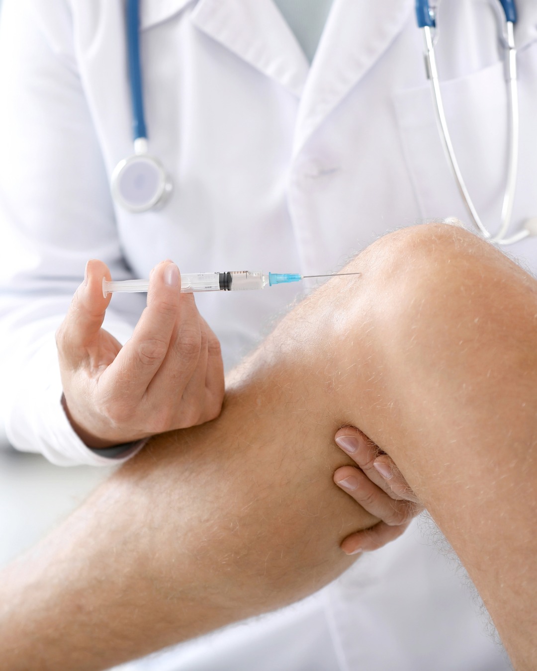 Doctor inyectando la rodilla de un paciente