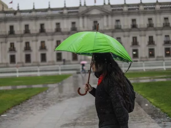 Persona con un paraguas bajo la lluvia frente a La Moneda