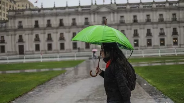 Persona con un paraguas bajo la lluvia frente a La Moneda