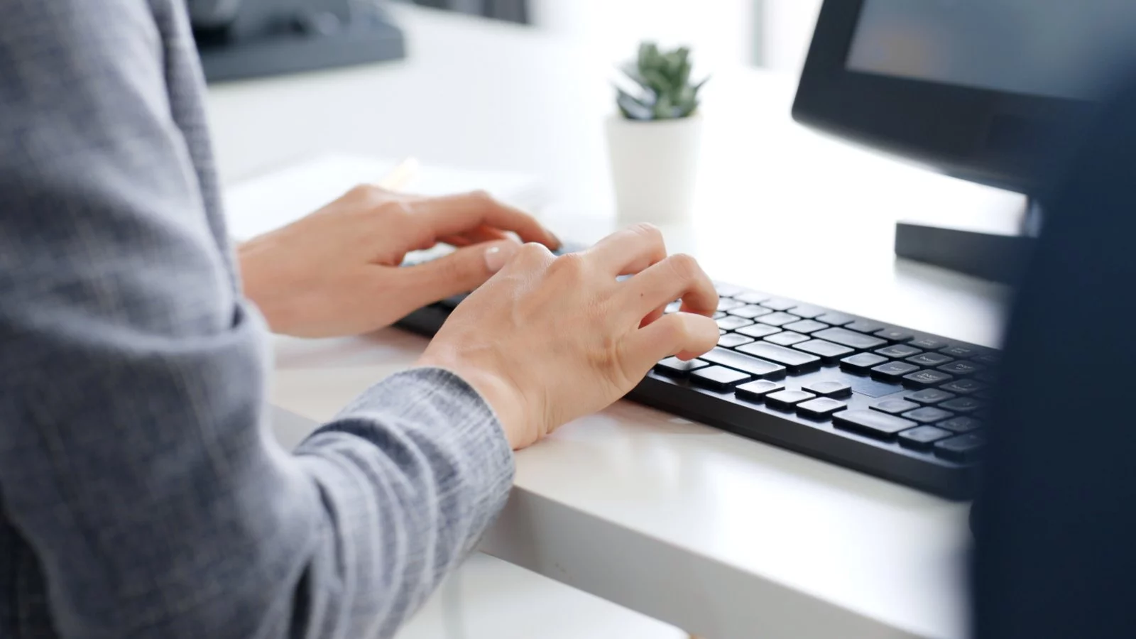 Persona en un escritorio escribiendo en un teclado de computador