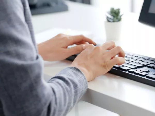 Persona en un escritorio escribiendo en un teclado de computador