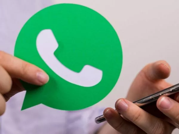 Logo de WhatsApp y persona revisando su celular